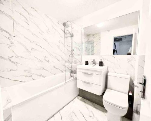 een witte badkamer met een toilet en een bad bij Modern Gem Apartment in Deptford with parking in Londen