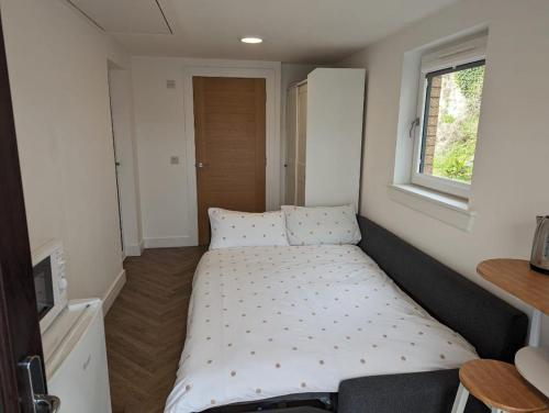 Posto letto in una piccola camera con finestra di En-suite double room with private entrance a Edimburgo