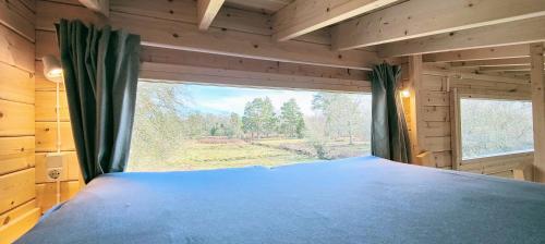 ein Schlafzimmer mit einem großen Fenster in einem Blockhaus in der Unterkunft Tiny houses Liv & Lea in Listerby