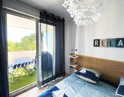 Schlafzimmer mit einem Bett und einem Kronleuchter in der Unterkunft Nouveau ! Spacieux T2 climatisé au calme, parking in La Grande-Motte