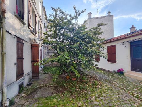 a tree in an alley between two buildings at Comfy Parisian studio! in Ivry-sur-Seine