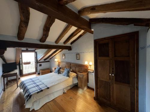 a bedroom with a large bed in a room with wooden beams at Posada la Trebede in Perrozo