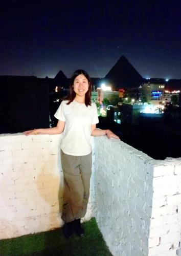 a woman standing next to a brick wall at night at Eyad Pyramids view in Cairo