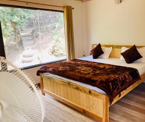a bedroom with a bed with a large window at Sattal Valley Resort in Bhīm Tāl