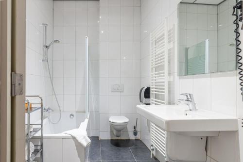 La salle de bains est pourvue d'un lavabo, de toilettes et d'une douche. dans l'établissement Hotel - Brasserie Ingredi, à Brée