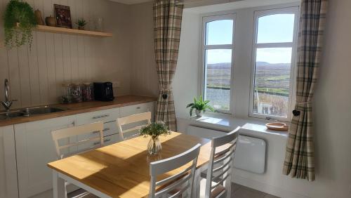 una cucina con tavolo in legno e finestra di An Cnoc Bed & Breakfast a Staffin