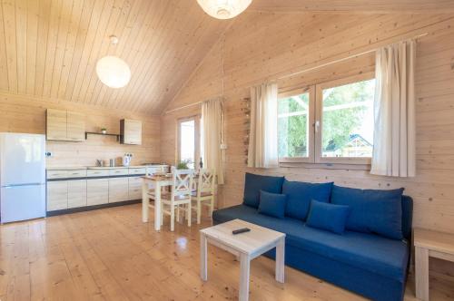 a living room with a blue couch and a kitchen at Morska Polana in Mielno