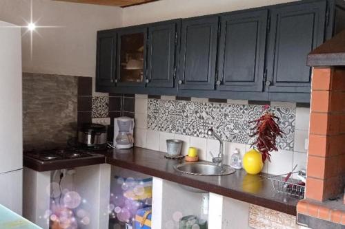 una cocina con armarios negros y fregadero en Grande villa avec piscine et clim proche de la mer, en Marsillargues