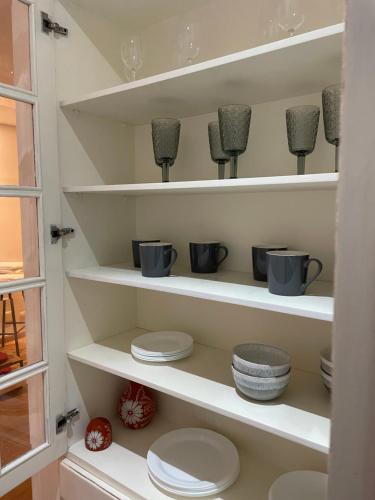 una despensa con estanterías blancas con tazas y platos en Quatre Saisons Residence, en Campos do Jordão