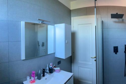 ein Bad mit einem Waschbecken, einem Spiegel und einer Dusche in der Unterkunft Country House Lake front in Azzate