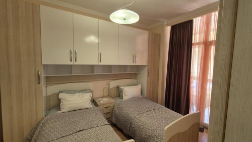 a room with two beds and a cabinet and a window at Aurora appartment in Tirana