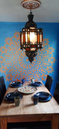 a chandelier hanging over a wooden table with plates and bowls at Chalet Veluwe G10 Veldkamp 4 Personen in Epe