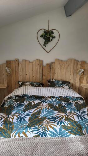 uma cama com uma cabeceira de madeira e um relógio na parede em Les bastides de la plage-400 m de la plage em Le Grau-du-Roi
