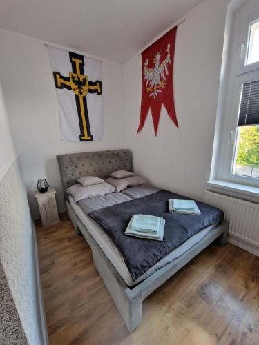 a bedroom with a bed with flags on the wall at Apartamenty Zakonne "Apartament Rycerza" in Malbork