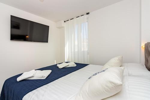 a white bedroom with a bed with a tv on the wall at House Feral (Vis center) in Vis