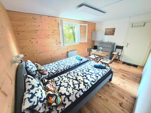 een slaapkamer met een bed en een houten muur bij Romantischer studio mit grosser Terrasse in Salavaux