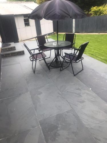 a patio with a table and chairs and an umbrella at House on the Furrows in Luton
