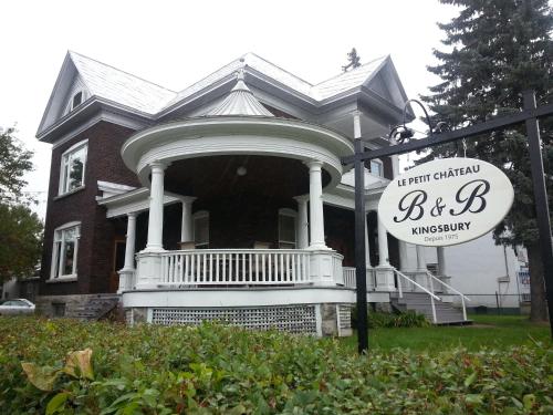 a large house with a sign in front of it at Le Petit Château Montebello B&B in Montebello