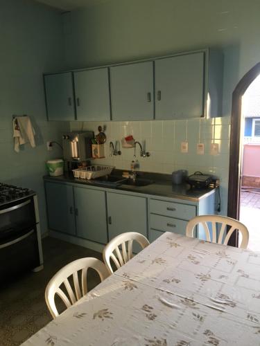 - une cuisine avec une table, des chaises et un comptoir dans l'établissement CASARÃO CAPITAL DO SURF SAQUAREMA, à Saquarema