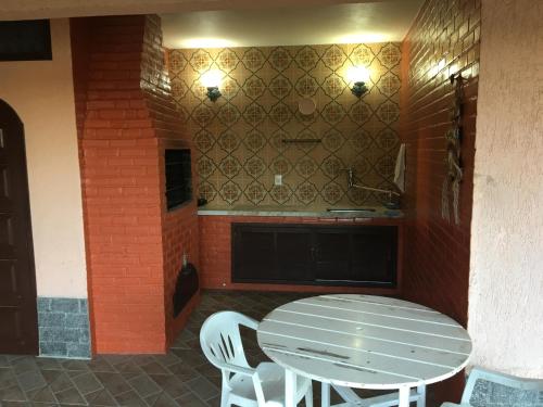 - une table et des chaises blanches dans la cuisine dans l'établissement CASARÃO CAPITAL DO SURF SAQUAREMA, à Saquarema