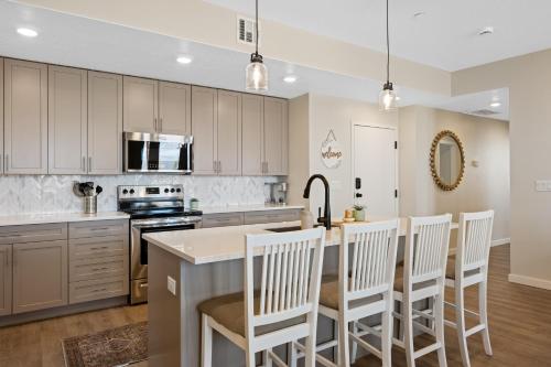 een keuken met witte kasten en een keukeneiland met witte stoelen bij Desert Oasis condo in St. George