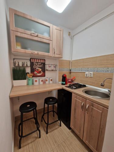una pequeña cocina con fregadero y 2 taburetes en House of colors, en Petroşani