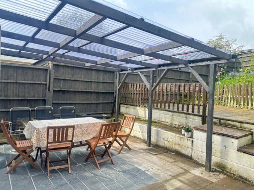 eine Pergola mit einem Tisch und Stühlen auf einer Terrasse in der Unterkunft Deluxe Bungalow in Longham