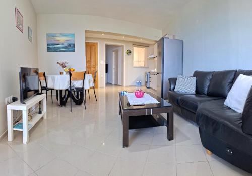 ein Wohnzimmer mit einem schwarzen Sofa und einem Tisch in der Unterkunft Maria's urban seaview apartments in Iraklio