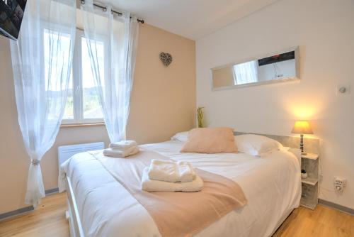 a bedroom with a white bed with towels on it at Le Déroc - Netflix Wi-Fi Fibre Terrasse in Banassac