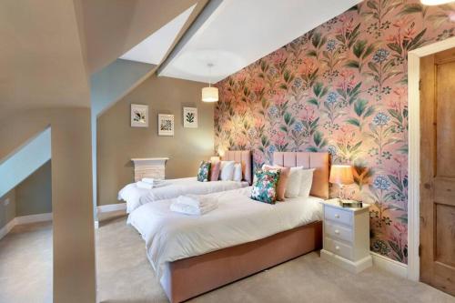 two beds in a room with a floral wallpaper at The Olive Suite - 3 bedroom - Free Parking in Harrogate