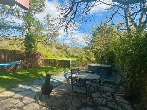 un patio con tavolo e sedie in un cortile posteriore di Cosy Country Cottage in Eryri Snowdonia with Hot Tub near Cardigan Bay a Llanbedr