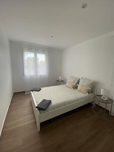 une chambre blanche avec un lit et un parquet dans l'établissement Maison moderne plain pied, à Saussan