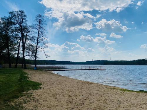 a sandy beach with a dock in the water at Przytulne Kątno in Kątno