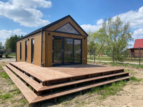 a small cabin with a wooden deck in a field at Przytulne Kątno in Kątno