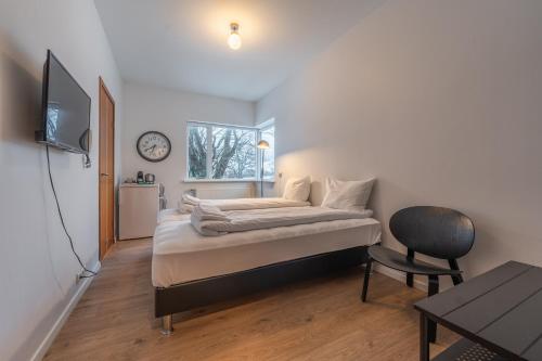 a bedroom with a bed and a chair and a clock at Day Dream Soleyjargata Rooms & Apartments in Reykjavík