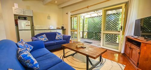 a living room with a blue couch and a table at Tipani Lodge - Free and Unlimited Wifi in Rarotonga