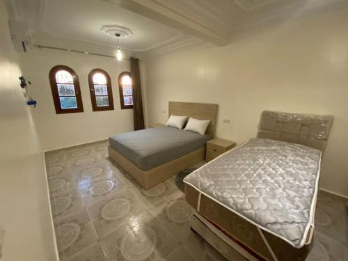 1 Schlafzimmer mit 2 Betten und 2 Fenstern in der Unterkunft Lina’s house in Martil