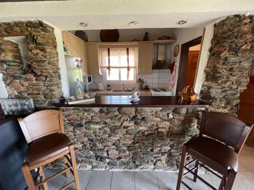 a kitchen with a stone wall and two chairs at Hope's House in Platanitis