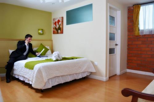 a man sitting on a bed in a room at Kuna Hotel in Cuenca