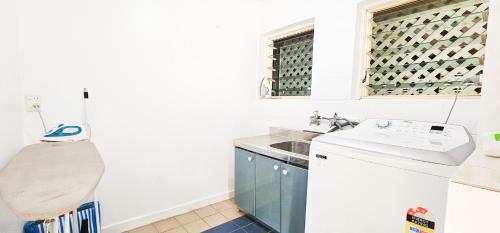 a kitchen with a sink and a window with wine bottles at Tipani Lodge - Free and Unlimited Wifi in Rarotonga