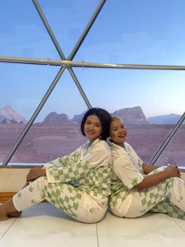two women sitting on the floor in the desert at Rum Green Camp in Wadi Rum
