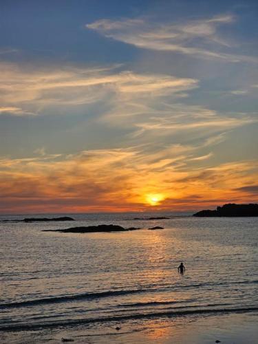 a person in the water at the beach at sunset at Morlun, Trearddur Bay, Isle of Anglesey in Trearddur