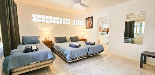 two beds in a room with a bathroom at Tipani Lodge - Free and Unlimited Wifi in Rarotonga