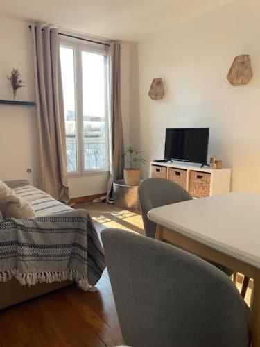 un salon avec une table, des chaises et une télévision dans l'établissement Charmant studio aux portes de Paris, à Saint-Ouen
