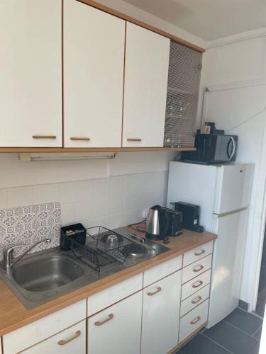 une petite cuisine avec un évier et un réfrigérateur dans l'établissement Charmant studio aux portes de Paris, à Saint-Ouen