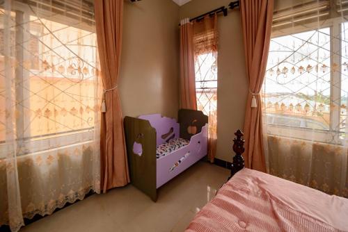 a childs bedroom with a purple crib and windows at PNG Guest house Kitende in Kampala