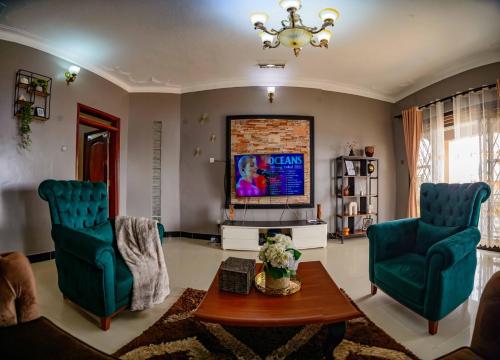 a living room with two green chairs and a tv at PNG Guest house Kitende in Kampala