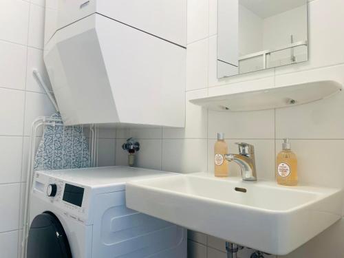 a bathroom with a sink and a washing machine at APSTAY Serviced Apartments - City Center - FREE Parking - Self Check-in in Graz