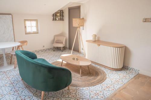 a living room with a green chair and a table at Château du Parc - Gîtes & spas à Pézenas in Pézenas