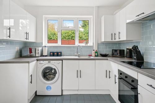 a white kitchen with a sink and a washing machine at No stress in Trumpington